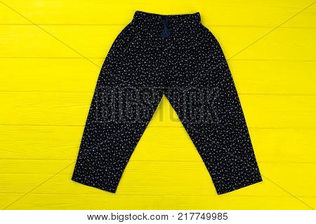 Floral pants on yellow wooden table. Loose fitting and comfy loungewear item. Bright clothing background for special offer.