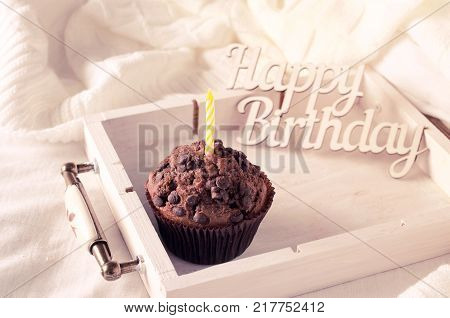 Birthday muffins or capkakes with chocolate on a wooden tray in bed. White background. Sweet food. Festive mood copy space flat lay