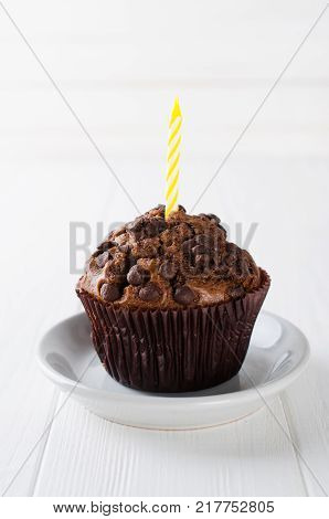 Birthday muffins or capkakes with chocolate and candle on a white wooden table. White background. Sweet food. Festive mood copy space flat lay