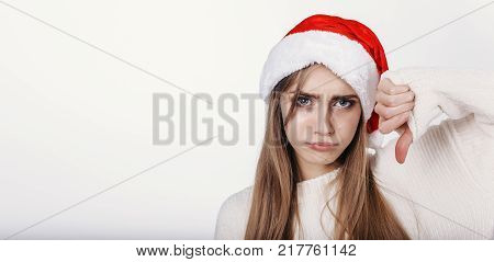 The Young Woman In Santa Hat Showing Thumbs Down And Make Capricious Face