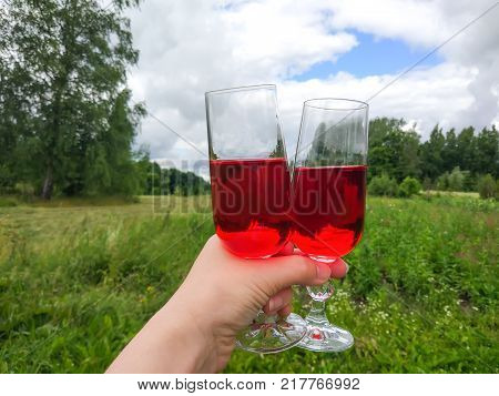 Two Glasses With Homemade Red Wine In A Hand On Farm Yard Background In Countryside At Summer.