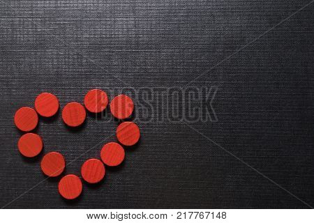heart of red wooden chips on a black textured background