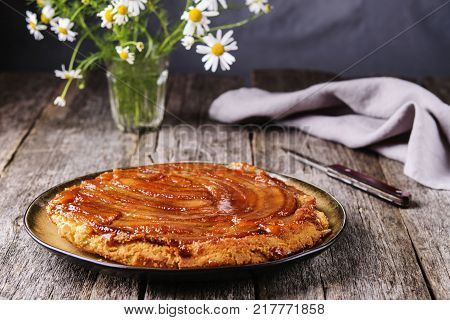 Traditional homemade banana caramel pie on vintage wooden table decorated a bouquet of chamomiles.  Upside down banana cake. Selective focus