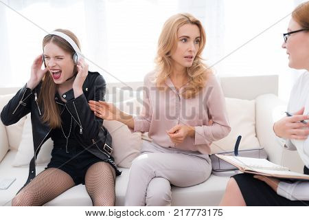 A teenage girl with her mother at a psychologist's reception. The girl has a complicated character. She does not listen to adults. She loves rock music and dressed in a leather jacket.