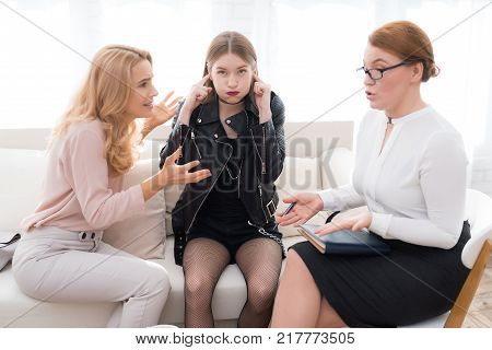 A teenage girl with her mother at a psychologist's reception. The girl has a complicated character. She does not listen to adults. She loves rock music and dressed in a leather jacket.