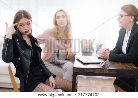 A teenage girl with her mother at a psychologist's reception. The girl has a complicated character. She does not listen to adults. She loves rock music and dressed in a leather jacket.