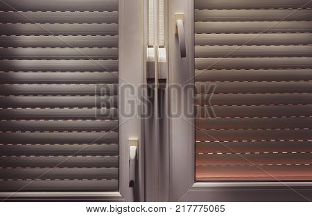 Closed aluminum blinds view from inside, accentuated shapes with light.