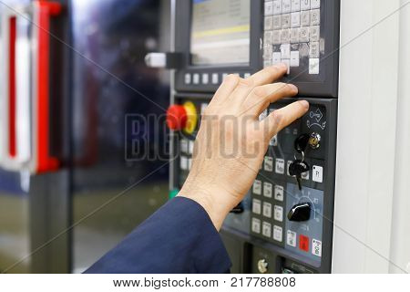 Operator working with CNC machining center using control panel. Selective focus.