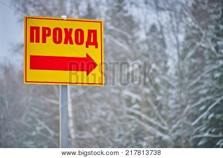 Yellow direction sign with red word and arrow on winter forest background