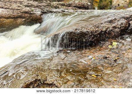 Powerful mountain river close up. Crystal water flows through mossy boulders and rocks. Dark vintage toning filter. Buky Canyon on the Hirs'kyi Tikych river in Ukraine.