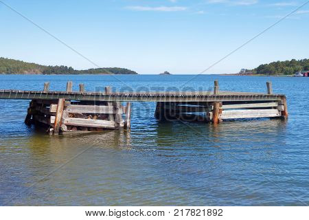 Wooden bridge in the blue sea islets in the Finish archipelago in the background