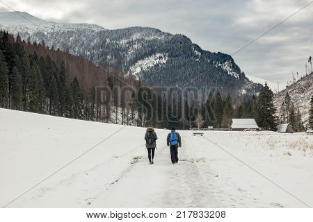 A couple walks on a snow-covered valley in the mountains