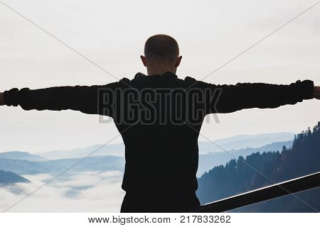 A young guy stands on top of a mountain
