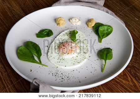 Single Fried Egg In Egg Shape Over White Plate Garnished With Spinach Green Herbs Salt Papper Horser