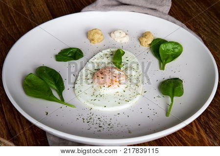 Single Fried Egg In Egg Shape Over White Plate Garnished With Spinach Green Herbs Salt Papper Horser