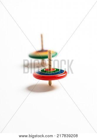 Two wooden top spinning, isolated on natural white background. Blurred effect of spinning, shallow depth of field.