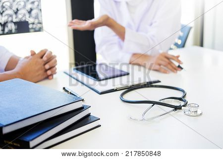 Professor Doctor discussion a method with patient treatment with Mammogram film x-ray of patient 's head for brain skull or eye injury and laptop computer on table.