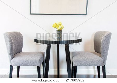 Yellow flowers in the vases on the table and chairs by the wall.