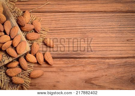 Raw almond nuts on a wooden background with copy space for text. Crunchy brown cased almonds. Good source of protein, fiber, vitamins and nutrients. Top view