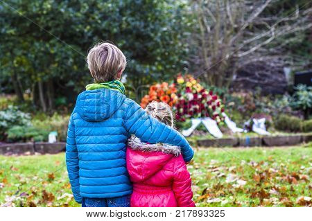 Little brother and sister standing at the grave of their parents in the graveyard
