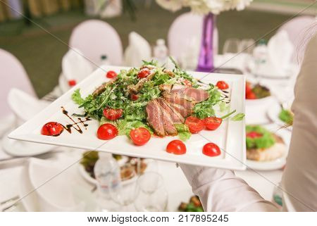 Fresh delicious lettuce on a dish in the hands of waiter