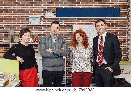 Portrait Of Office Staff Standing In Office. Team is looking at camera and smiling while standing in thei working space.