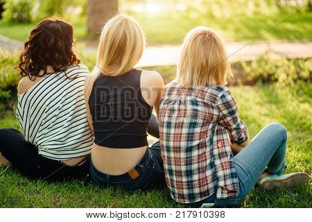 three girls having fun in the sunset park. rear view