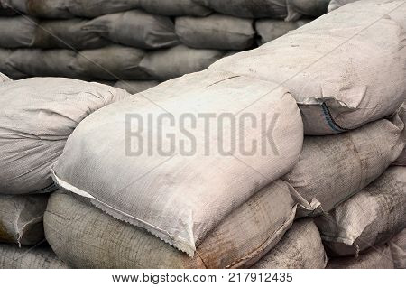 Background of many dirty sand bags for flood defense. Protective sandbag barricade for military use. Handsome tactical bunker