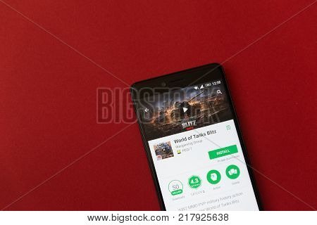 Los Angeles, december 11, 2017: Smartphone with World of tanks blitz game application in google play store on red background