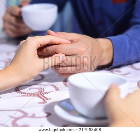 Male and female hands on table defocused. Rendezvous and coffee break concept. Couple in love holds cups of coffee at table. Woman and man have a date
