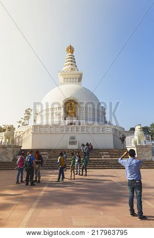 The young resident of India photographs the friends against the background of the Japanese shanti-stupa close to the place where Buddha has made the second turn of a wheel of the teaching. Radzhgir, State of Bihar India on February 1 2014
