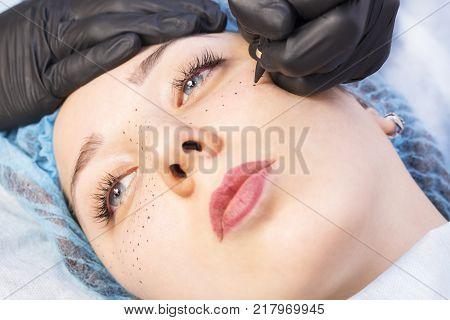 Permanent microblasting tattooing freckles to a woman in a beauty salon
