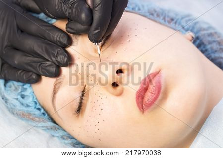 Permanent microblasting tattooing freckles to a woman in a beauty salon