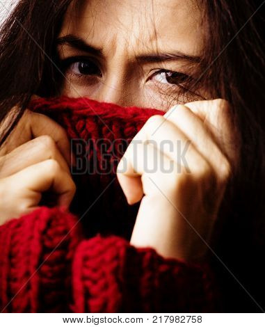 young brunette gloomy woman in sweater all over her face, messed hair close up