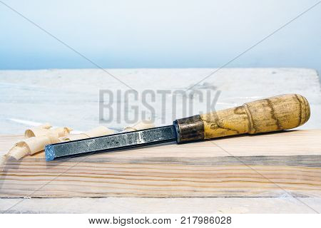 A carpenter's tool. Chisel on a wooden bar. Next to the chisel shaving