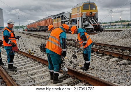 Tobolsk, Russia - July 15. 2016: Sibur company. Denisovka railway station. Railway workers repairing rail in rainy weather