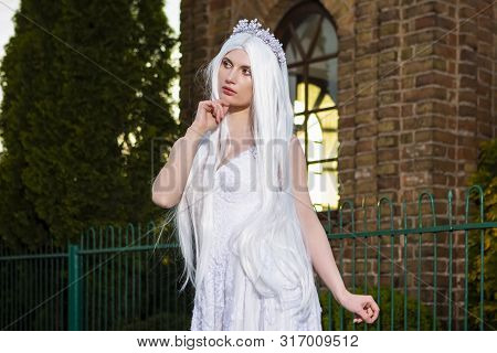 Young Sensual Caucasian Bride With Tiara And Long White Hair Posing In The City Outdoors. Horizontal