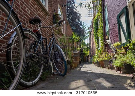 Leiden, Holland - July 05, 2019: Historical alley, Arend Roelandsteeg, in the center of Leiden with bikes and plants in summer  