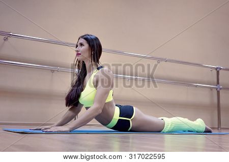 Girls Workout On Mat At Dance Hall Background. Cute Fitness Woman Lying On The Exercising Mat And Li