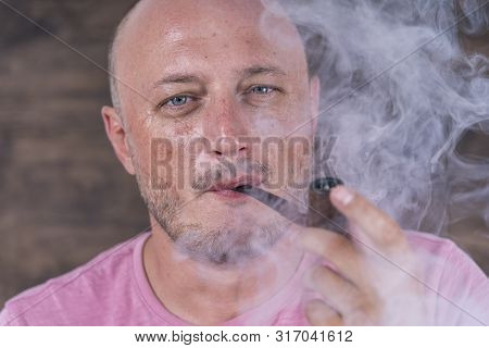 Man Smoking Pipe. Portrait Of Middle Aged Man Indoors. Bad Habits, Addiction. Unhealthy Lifestyle Co