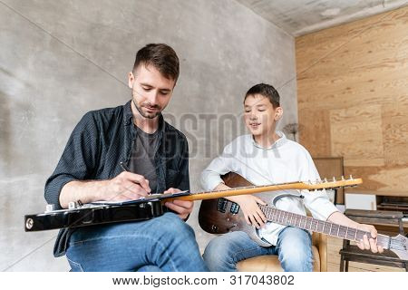 Older Brother Explains To His Younger One How To Use Notes On Music Sheets On An Exapmple