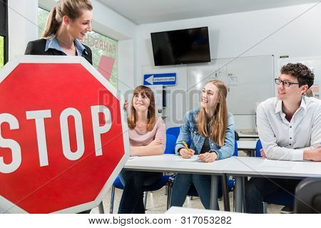 Driving instructor holding theoretical part of driving lessons with stop sign in her hand