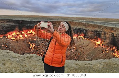 Turkmenistan, Darvaza - March 21, 2019:   Girl Makes Selfie On The Background Of The Burning Crater 