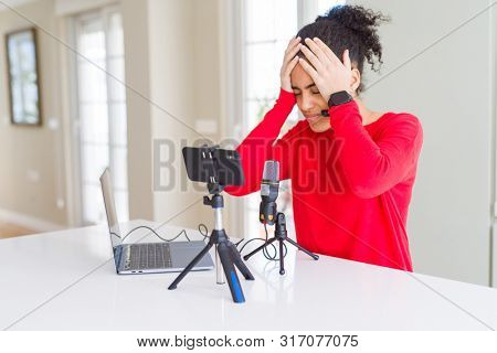 Young african american woman doing video call using smartphone camera and microphone suffering from headache desperate and stressed because pain and migraine. Hands on head.