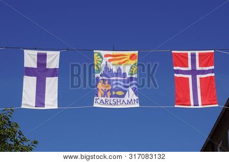 Karlshamn, Sweden - July 25, 2019: Flags Of Karlshamn City, Finland And Norway Against A Clear Blue 