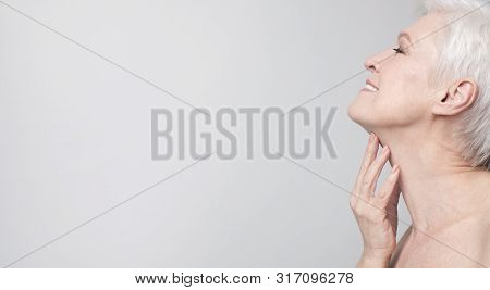 Aging Gracefully. Closeup Of Beautiful Senior Woman Touching Skin On Her Neck. Side View Panorama Wi
