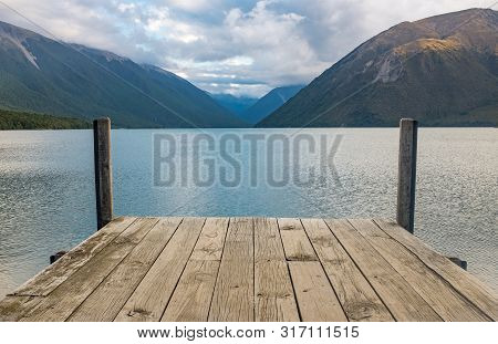 A View Down A Wooden Jetty Of The Incredibly Beautiful Rotoiti Lake Surrounded By Mountains Which Is