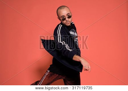 Studio Shot Of A Young Tattoed Bald Man Posing Against A Pink Background. 90s Style.