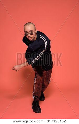 Studio Shot Of A Young Tattoed Bald Man Posing Against A Pink Background. 90s Style.