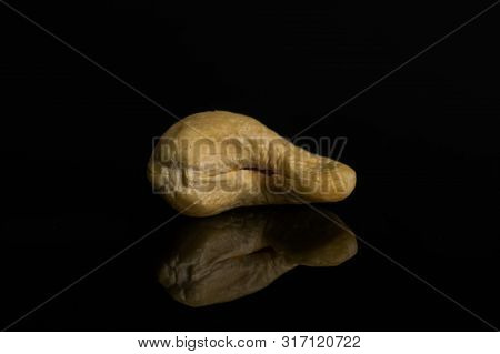 One Whole Unsalted Beige Cashew Isolated On Black Glass